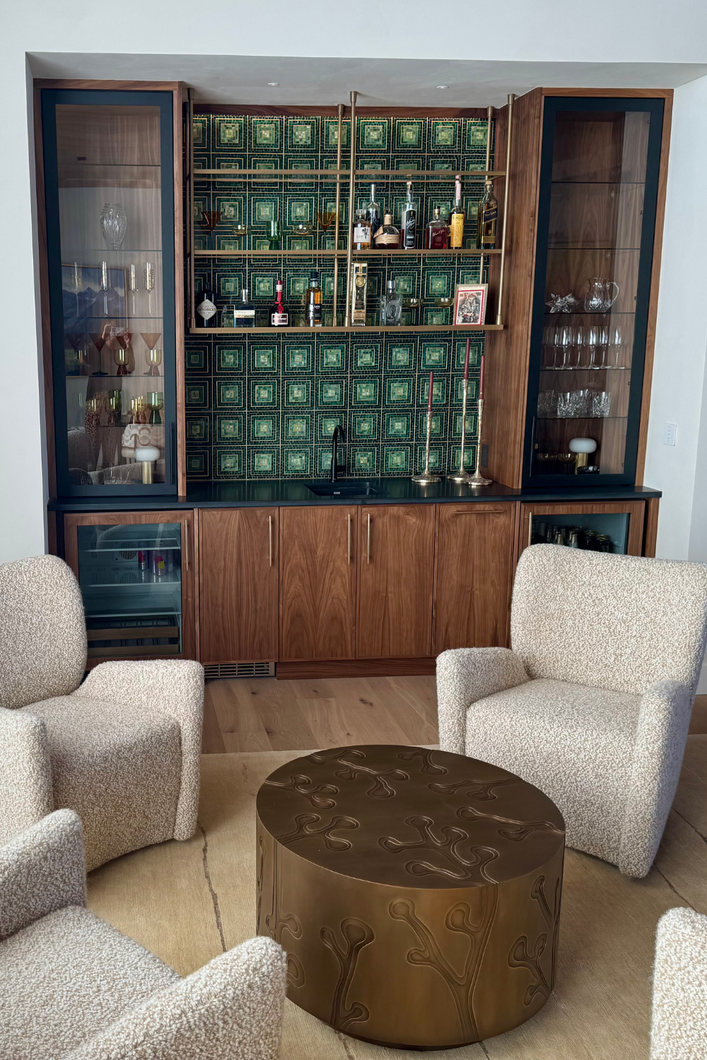 Wet bar cabinetry with gold ceiling mount shelves with bottles on display.